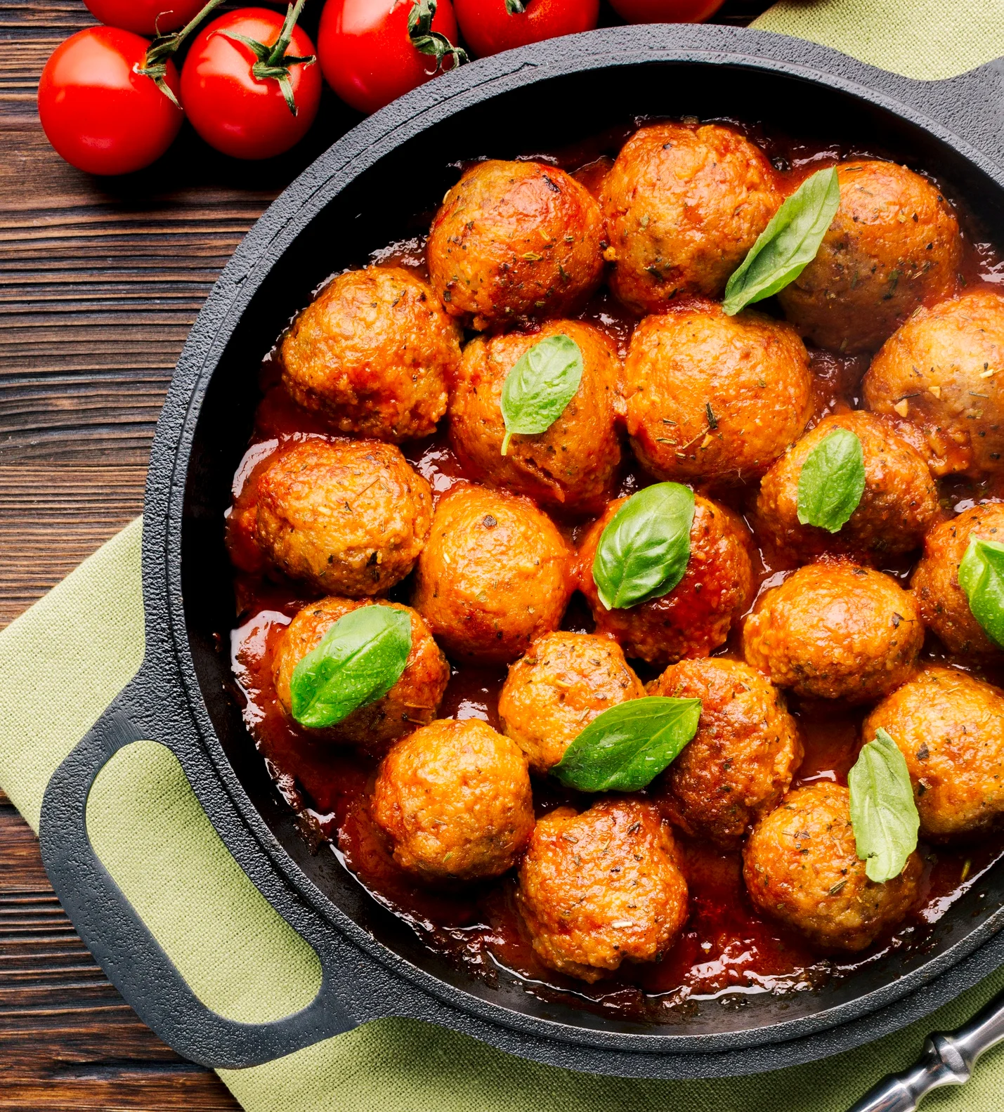 "Moroccan Kefta meatballs served in a traditional tagine, nestled in a vibrant tomato sauce, garnished with fresh cilantro, and accompanied by flatbread and couscous on a rustic table setting."