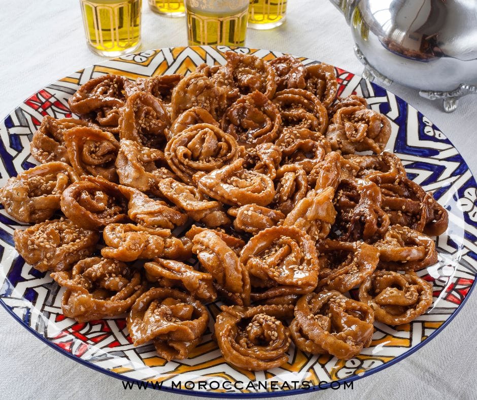 Moroccan Dessert Chebakya : Addictive Sweet Sensation 15 Hands shaping traditional Moroccan Chebakya dough into floral patterns on a floured table
