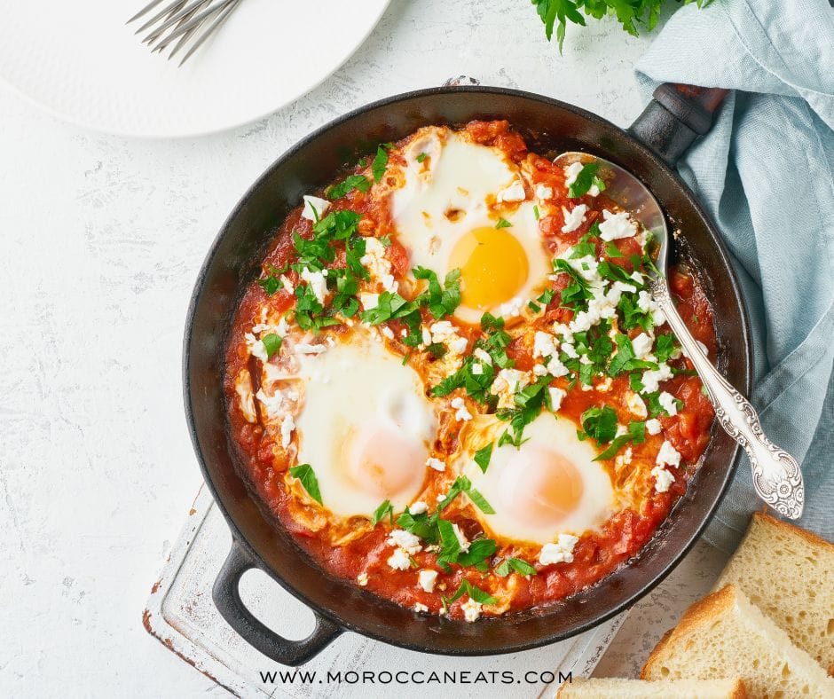 Moroccan-Style Shakshuka: The Addictive Brunch You Didn't Know You Needed 2 Moroccan-style shakshuka in a vibrant tomato sauce with eggs, herbs, and preserved lemon served with bread and tea.