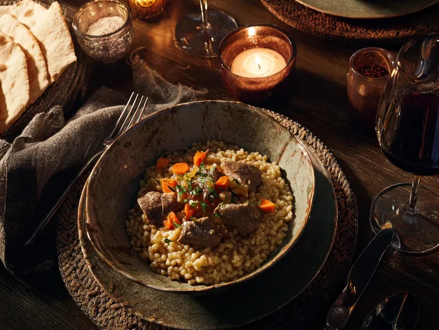 Moroccan Lamb Risotto: Irresistibly Flavor-Packed Delight 6 Dinner table with Moroccan lamb risotto, Moroccan carrot salad, flatbreads, and glasses of red wine in a warm, elegant setting