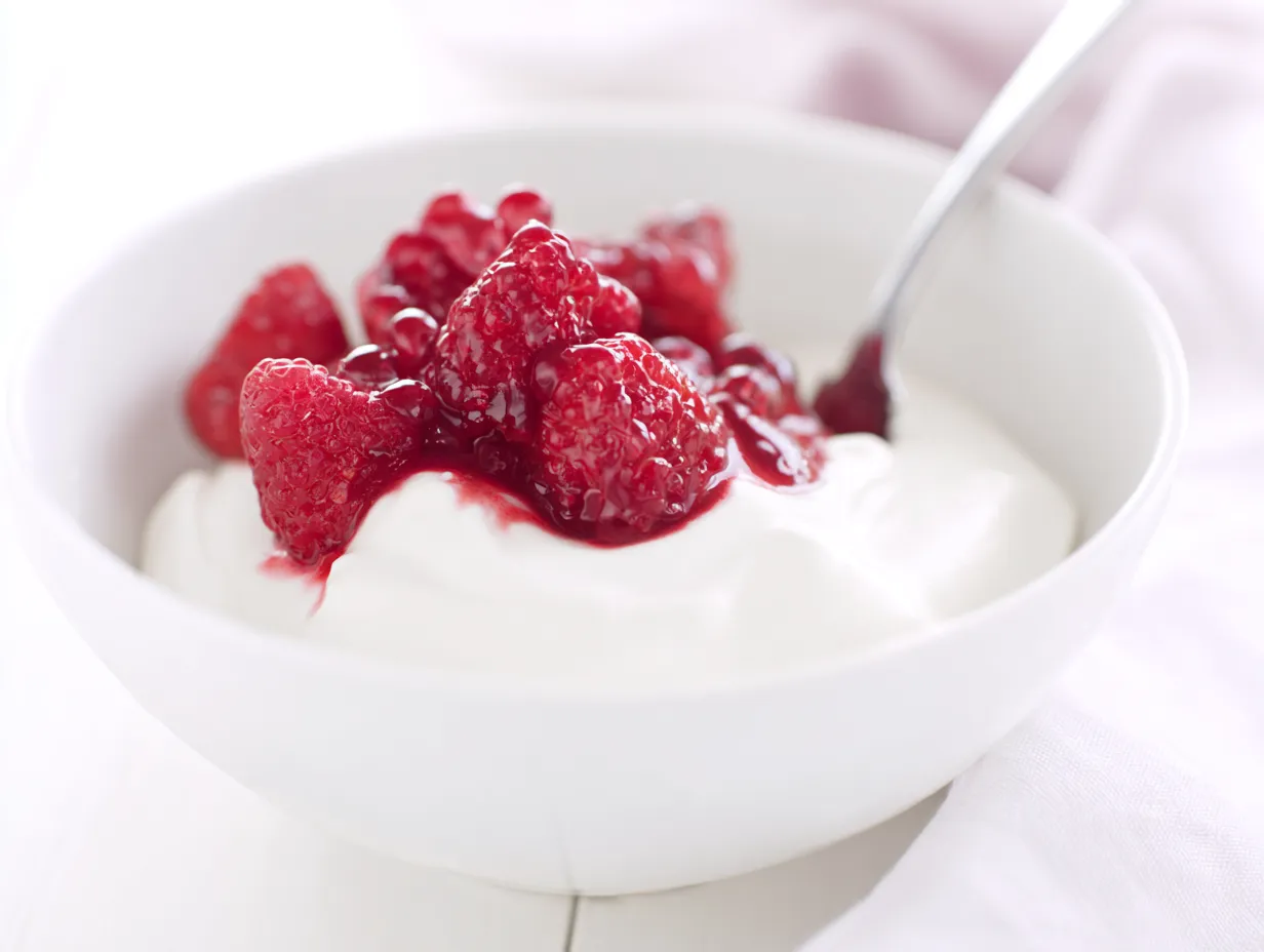 Raib with red berries and vanilla: Instantly Amazing 9 A white bowl of creamy, probiotic-rich homemade Moroccan Raib yogurt with fresh red berries and a spoon, highlighting its status as a healthy, refreshing summer dessert.